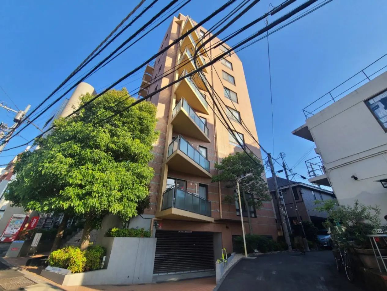 - モダンな外観のマンション、緑豊かな樹木と周囲の電線が特徴的な都市の景観