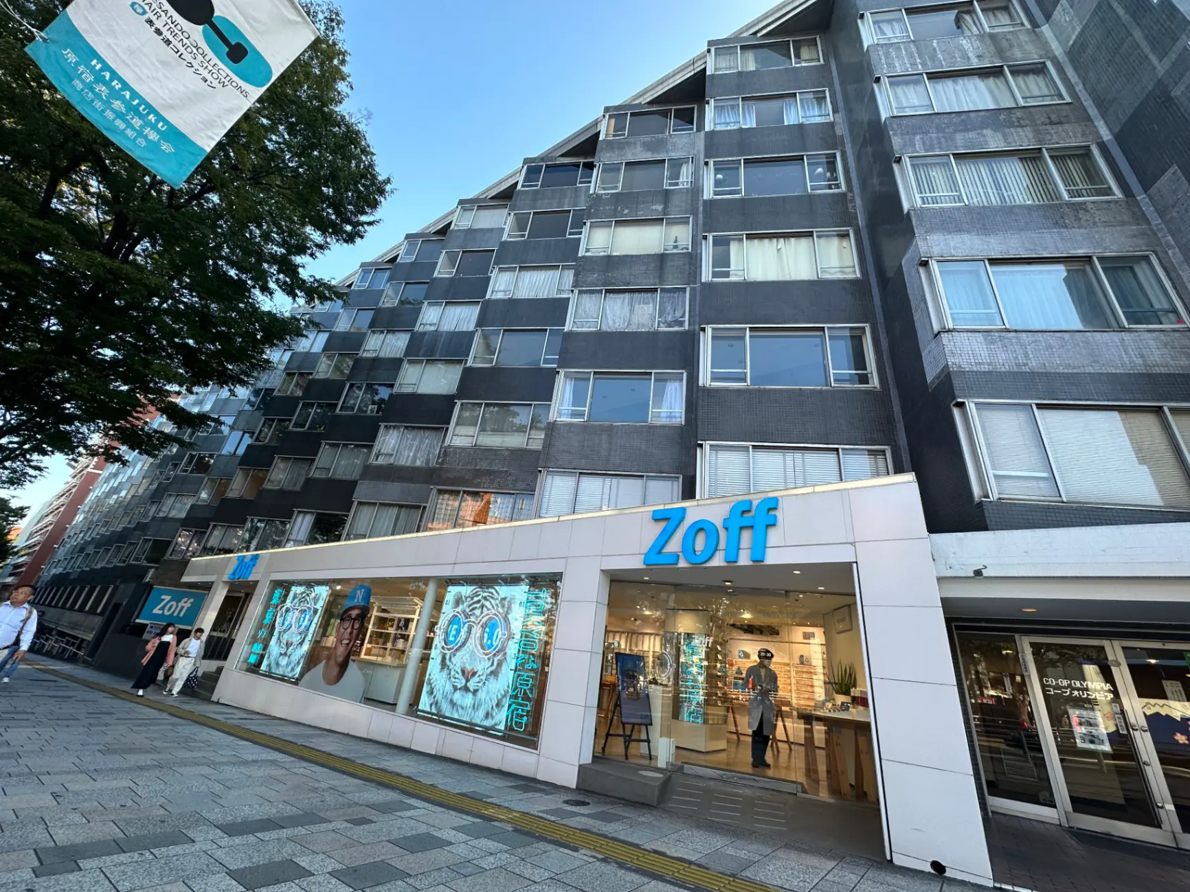 現代的な外観のZoffメガネ店舗、明るい看板とディスプレイウィンドウ、通行人が歩く歩道