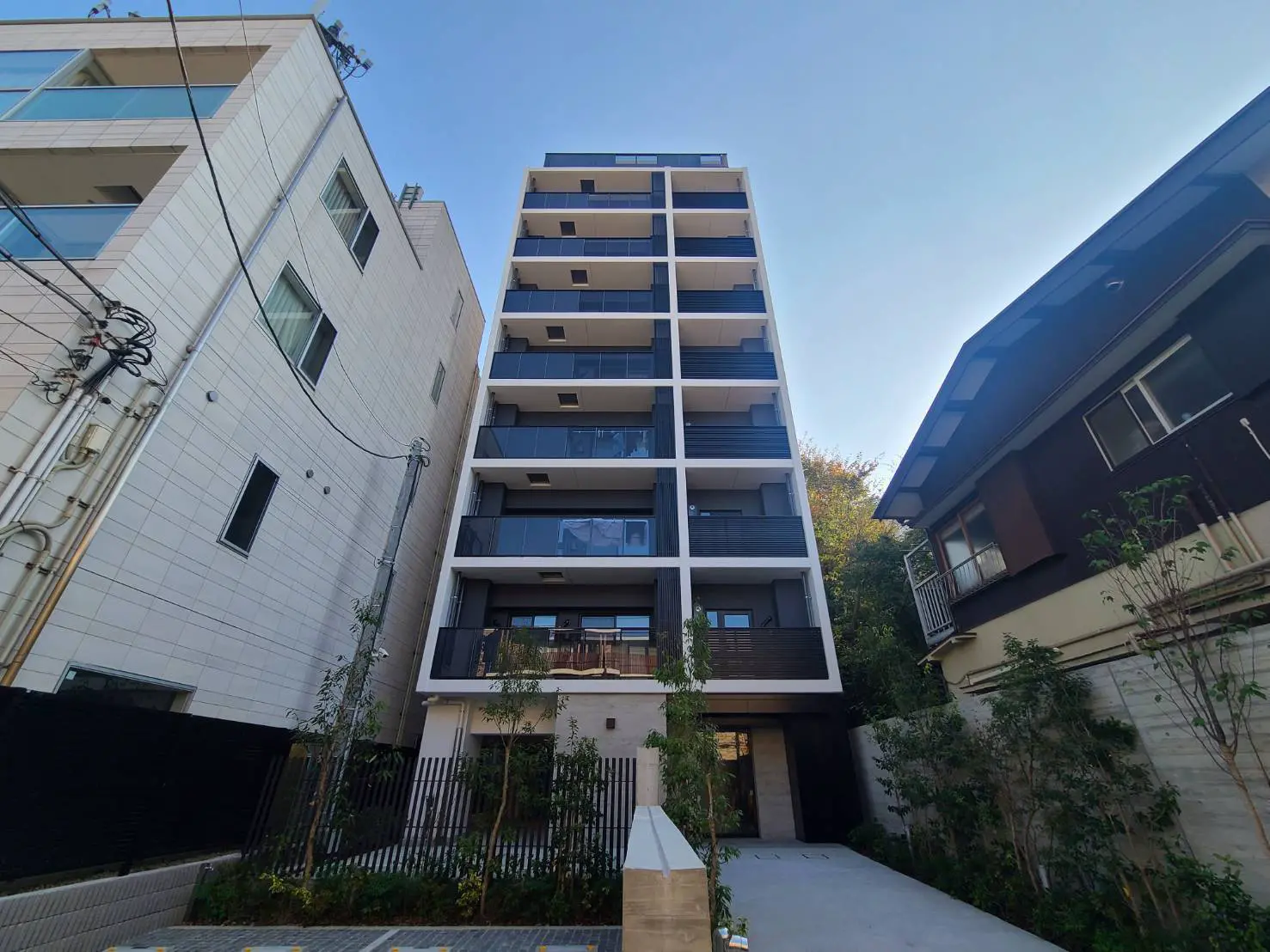 現代的な外観の日本のマンションと周囲の建物、晴れた日の青空