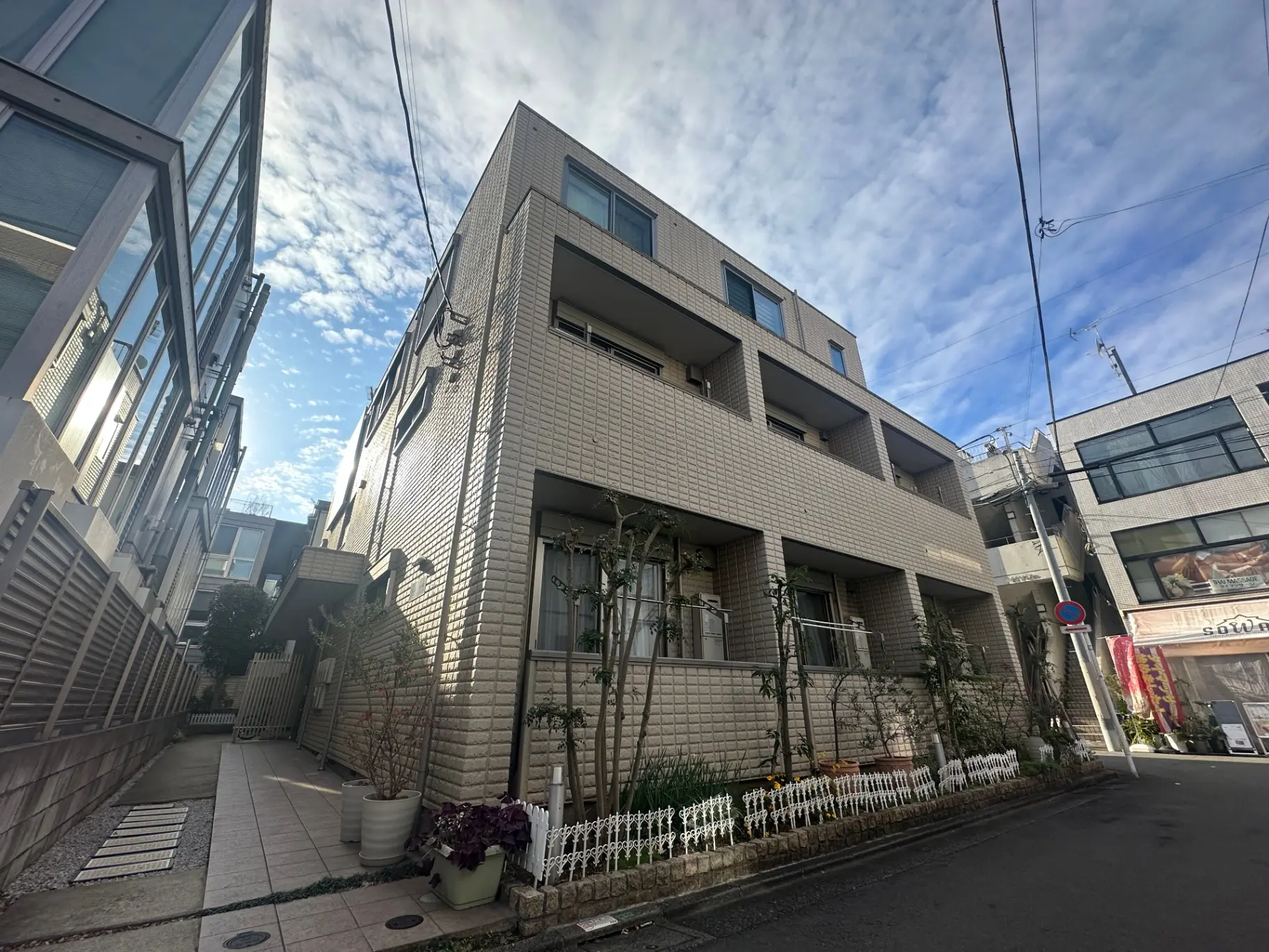 現代的な外観の都市型アパートメント、晴れた日の青空と共に街並みに溶け込むデザイン
