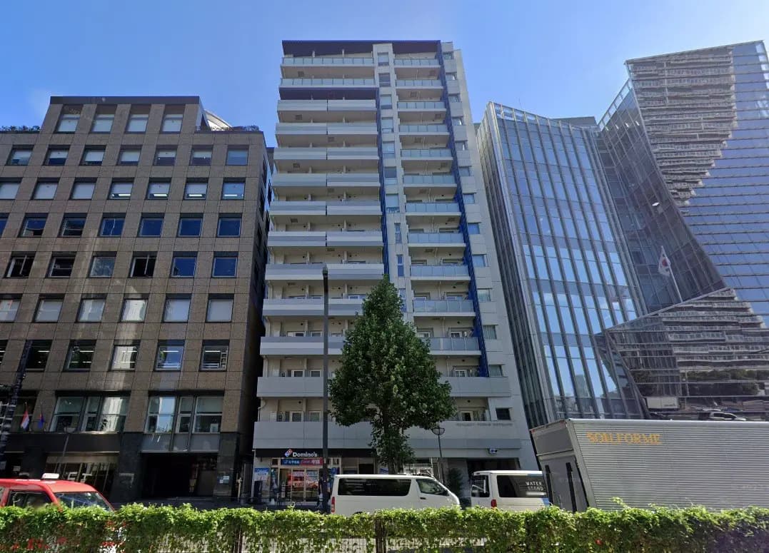 都市の中のオフィスビルとマンション、晴天の下でドミノピザの店舗が見えるストリートビュー