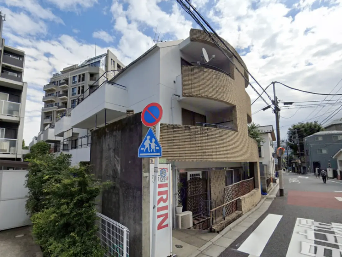- 曲線を描いたバルコニーを持つ現代的な建物と周囲の街並み、青空が広がる風景