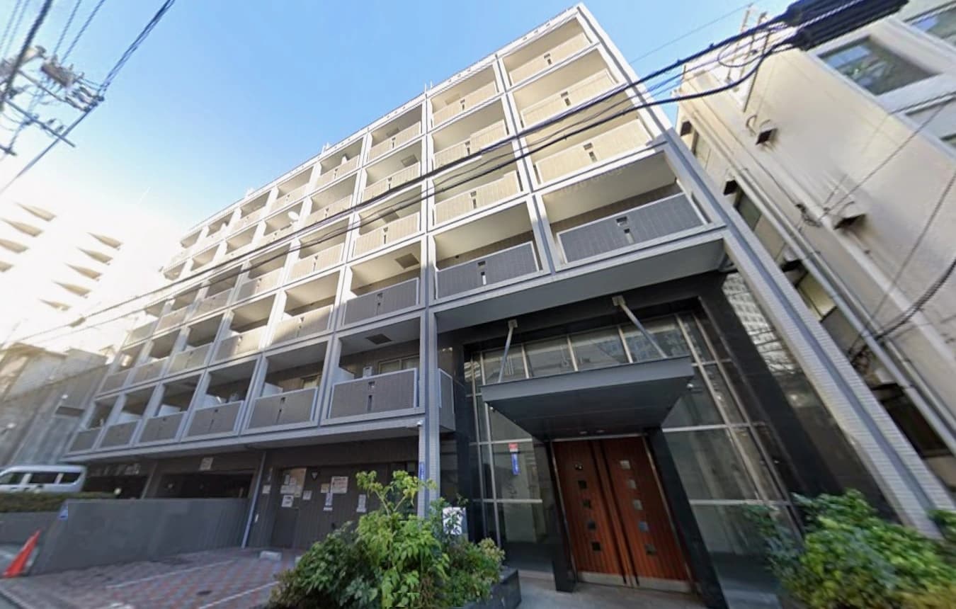 - 都心の高層マンション exterior、ガラスドアと木製ドアのエントランス、周囲に電線と都市景観が広がる風景