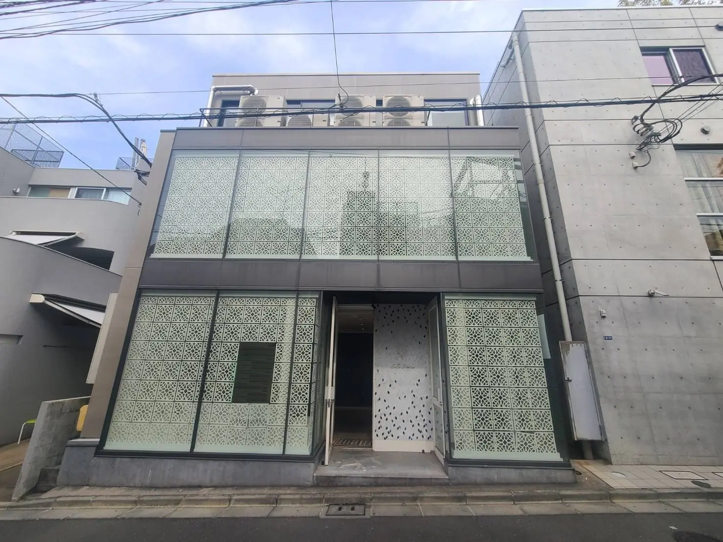 現代的な外観のビルディング、独特なデザインのパターンを施したガラス窓、コンクリートの壁