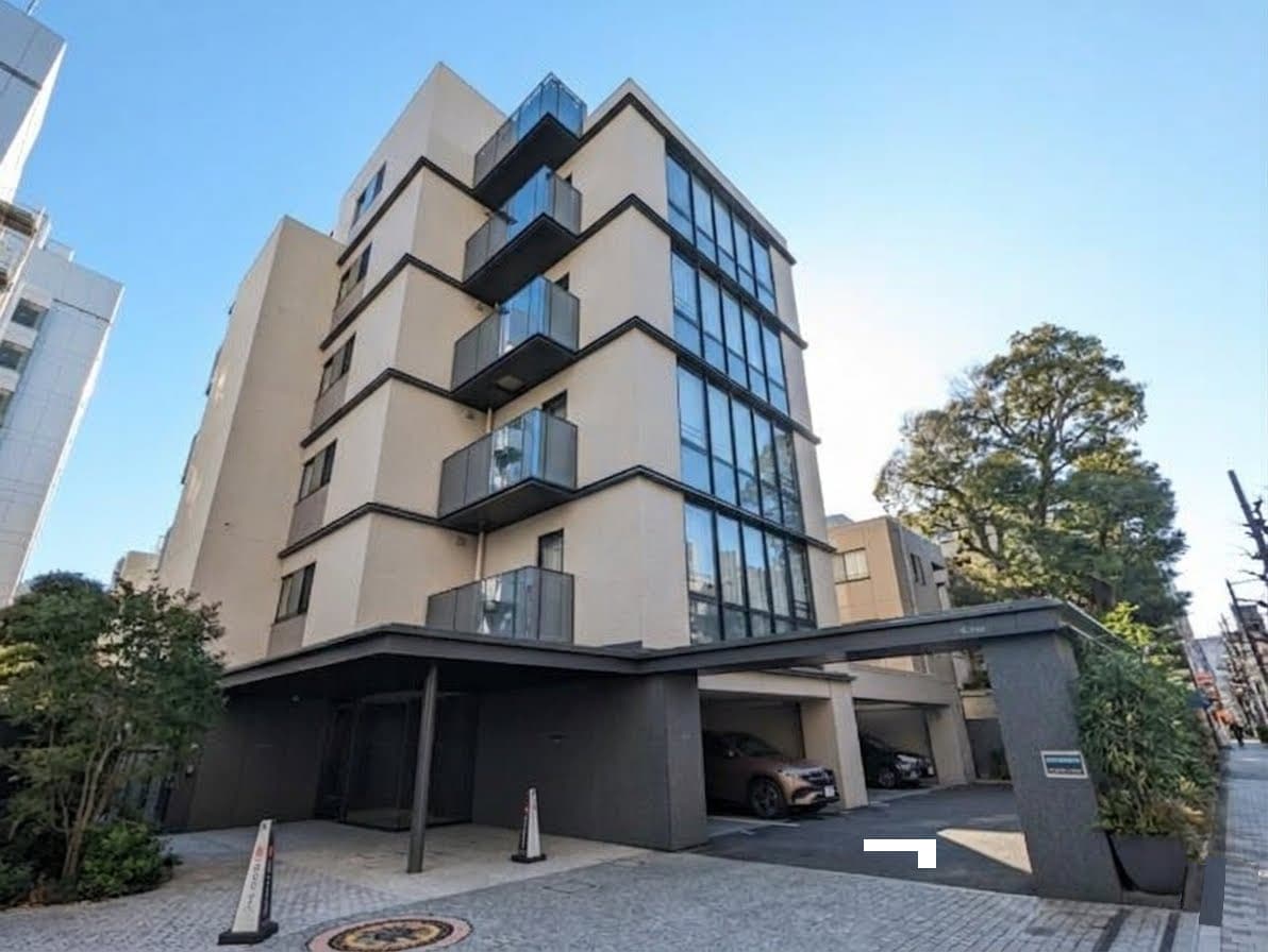 都会的な多階建てマンションの外観とエントランス、ガラス張りの窓とバルコニー、駐車場スペースと周囲の樹木が映えるモダンな建物の夜景とアプローチ