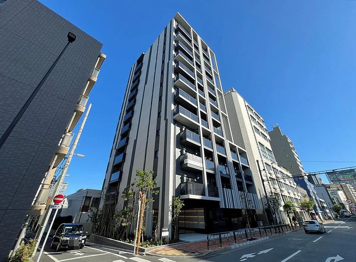新築高層マンションが立ち並ぶ繁華街の通り、ガラス張りのエントランスと水平のバルコニーが特徴的な都市景観