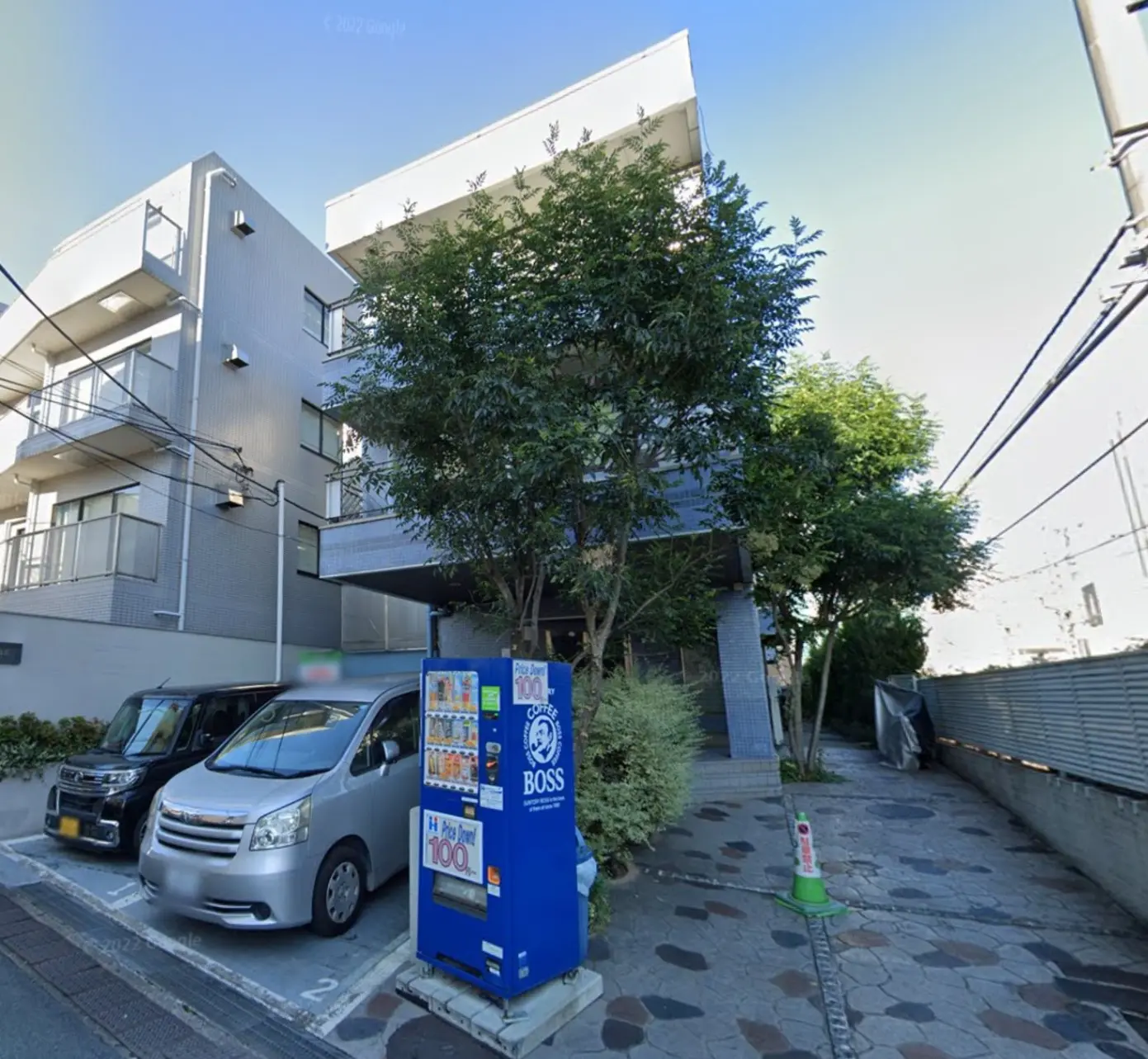 現代的な外観のオフィスビル、前に自動販売機と駐車している車、都市の景観