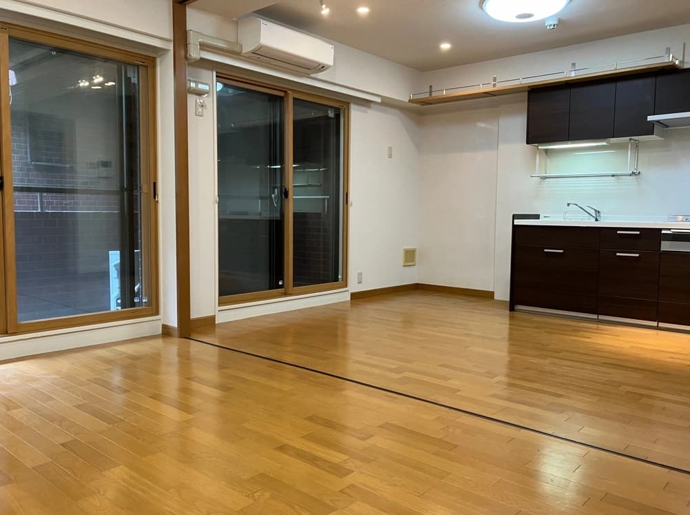 - 広々としたリビングダイニング、木目フローリングと大きな窓、開放的なキッチンが備わるモダンな室内